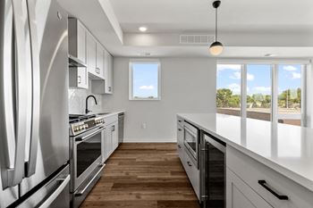 an empty kitchen with white cabinets and stainless steel appliances